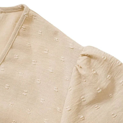 Close-up of the beige Abigail dress shoulder seam and flutter sleeve fabric