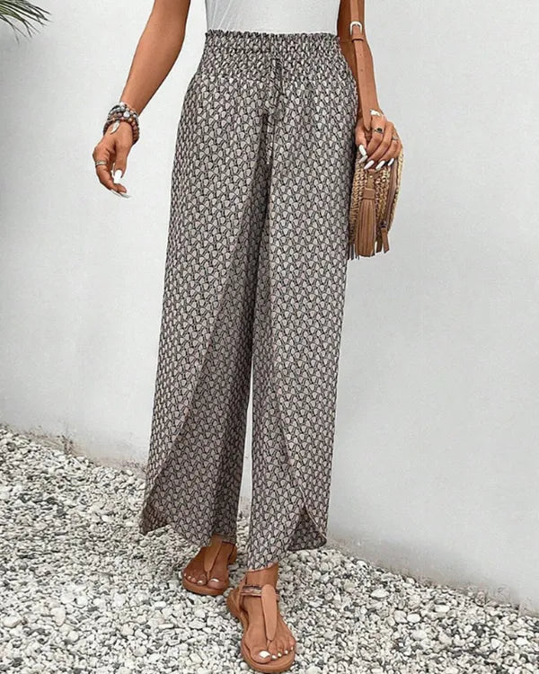 Lucie Women's Smocked Waist Palazzo Trousers in black floral, angled view with bag