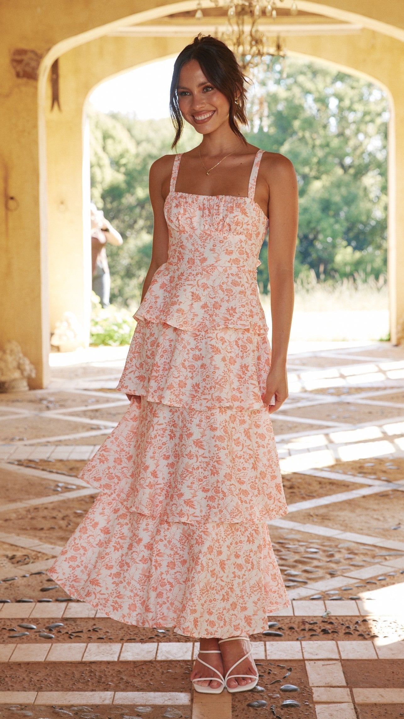 Alessandra pink floral tiered midi dress worn front-on under an archway