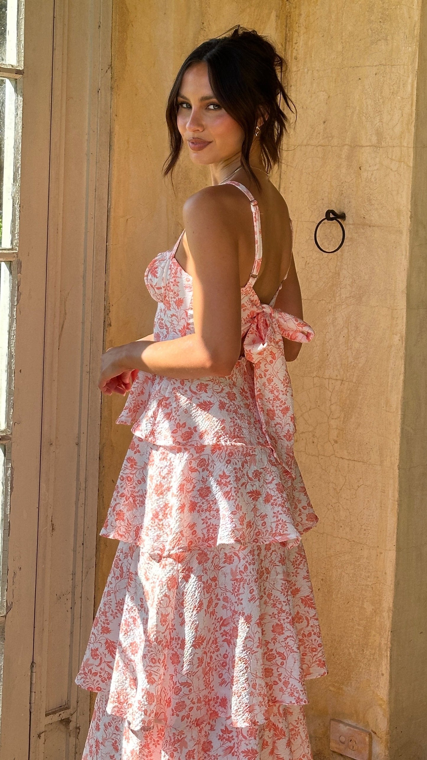 Pink Alessandra tiered floral midi dress seen from the side with bow tie