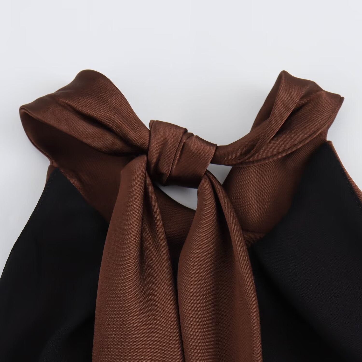 Detail of the brown halter tie bow at the back of the Juniper open back maxi dress