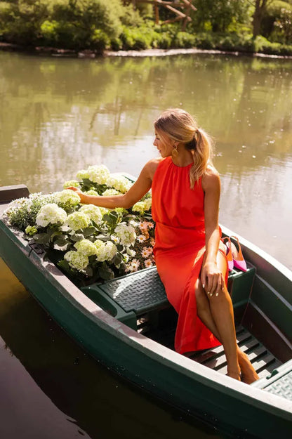 Orange Lacey halter midi dress seen from the side while seated in a boat