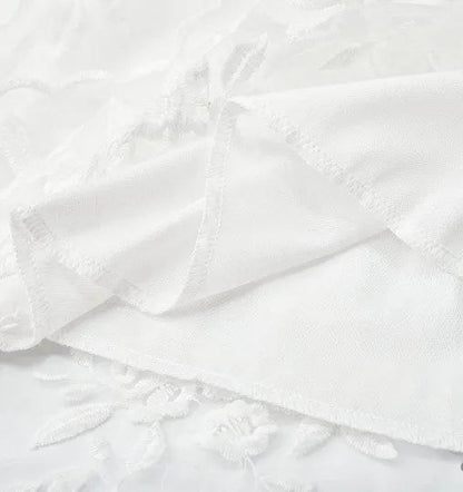 Close-up of the white floral lace fabric and scalloped hem of the Elsie dress