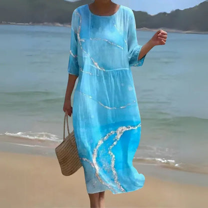 Sky blue Kallie caftan maxi dress with ocean print, front view on model at the shore