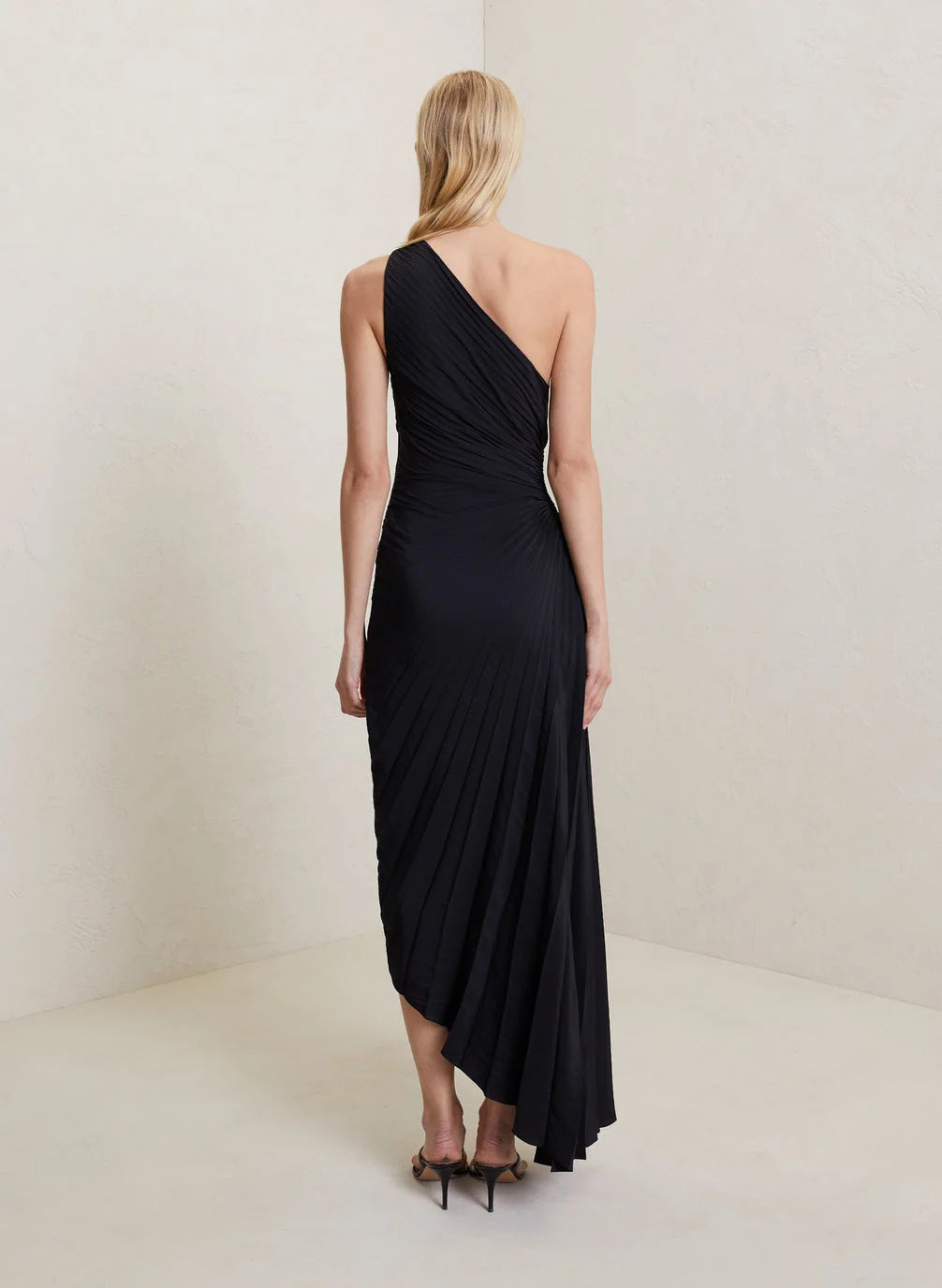 Back view of the black Inka one-shoulder pleated maxi dress and its hem