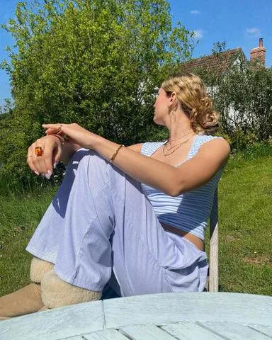 Belle Women's Pinstripe Pajama-Style Trousers in blue stripe, seated outdoor lifestyle shot