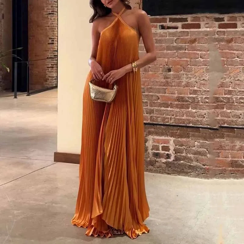 Hope orange pleated halter evening maxi dress, front view against brick