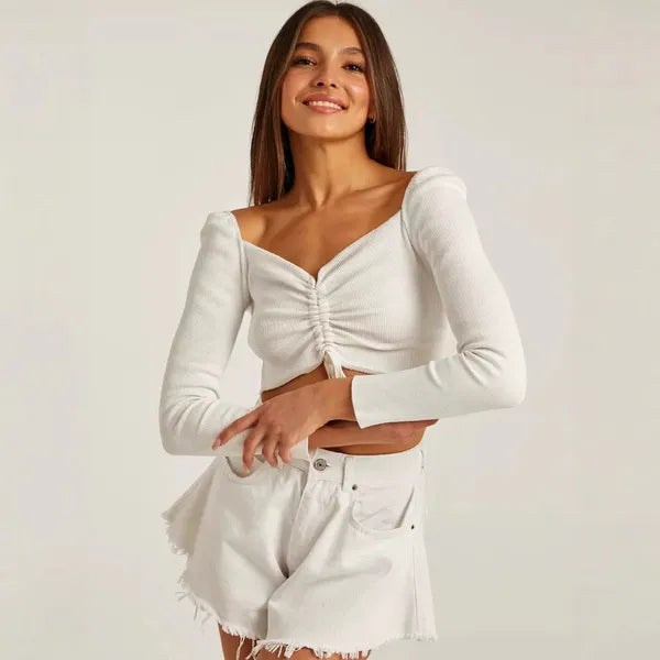 Lilou Women's Ruched Long Sleeve Crop Top in white, front view with denim shorts