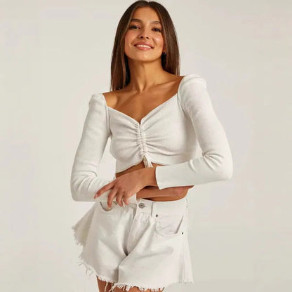 Lilou Women's Ruched Long Sleeve Crop Top in white, front view with denim shorts
