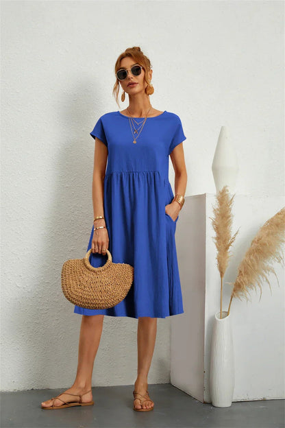 Henrietta women's shift summer midi dress in blue, front view on model with straw bag