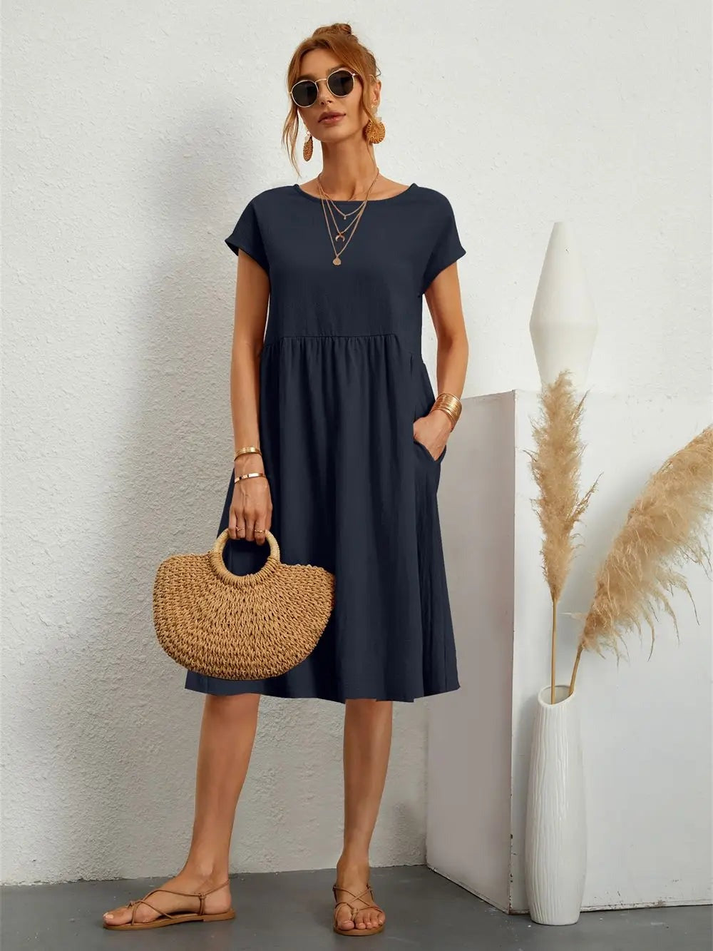 Henrietta women's shift summer midi dress in navy blue, front view with straw bag