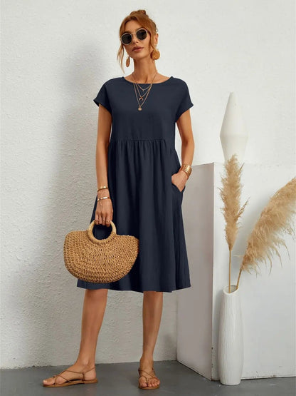 Henrietta women's shift summer midi dress in navy blue, front view with straw bag