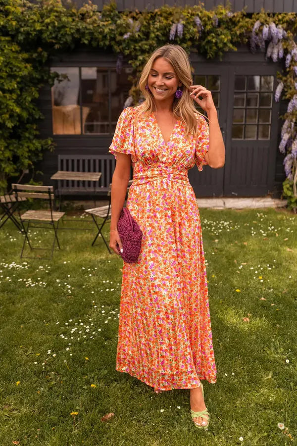 Lotte short sleeves floral maxi dress in orange, front view in a garden
