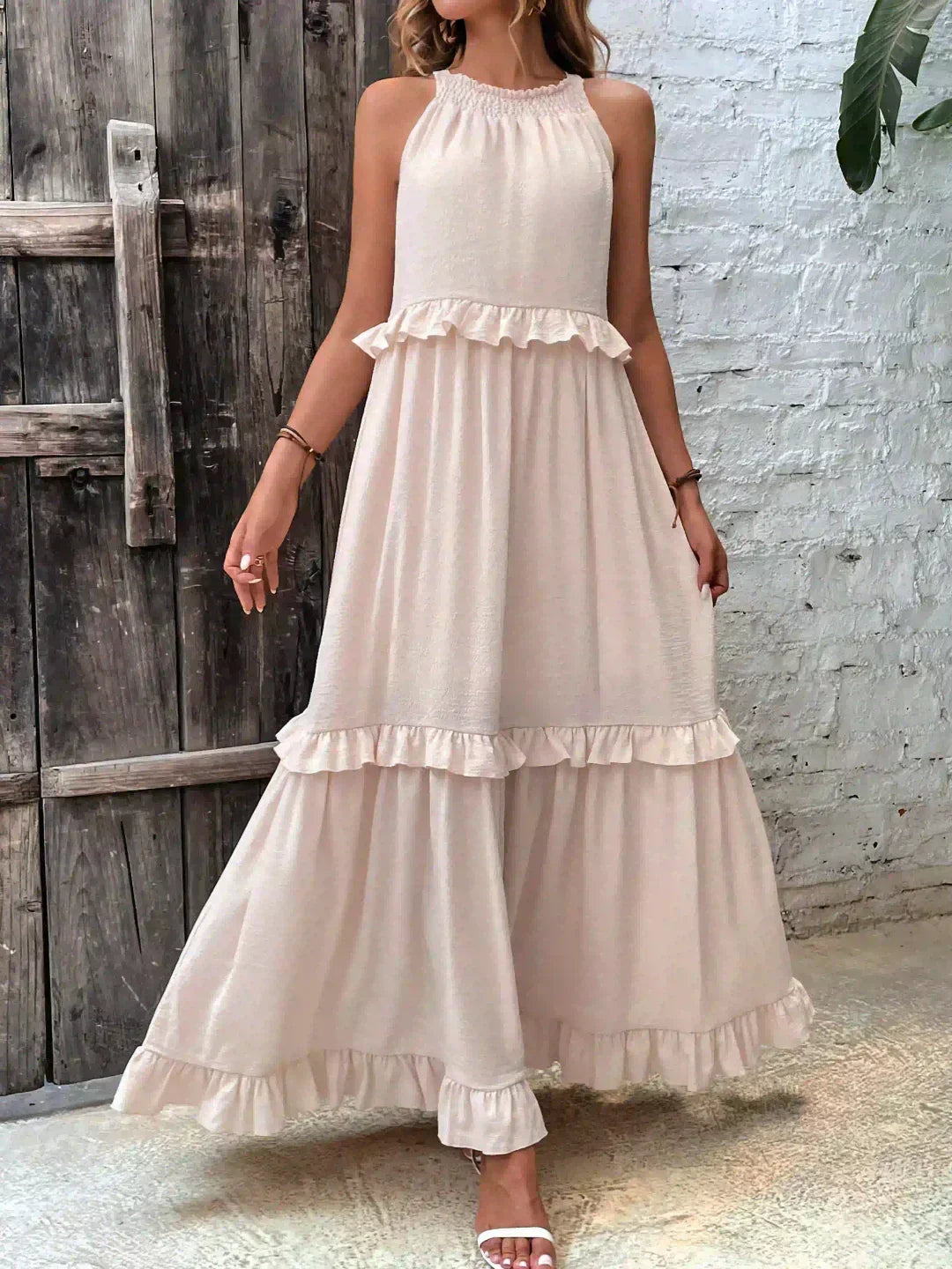 Kiersten beige sleeveless maxi dress front view against a rustic wooden door