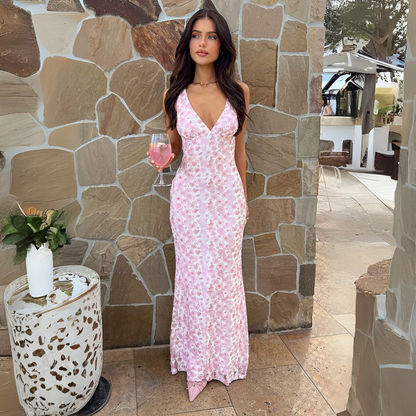 Model in the pink Florine floral maxi dress against a stone wall, front view