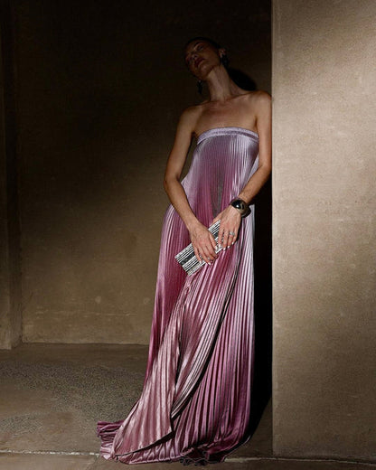 Side view of the pink ombre Grizel strapless pleated evening gown against a wall