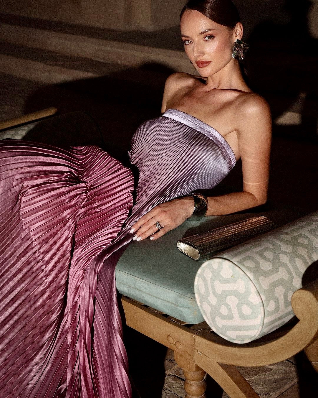 Model seated in the pink ombre Grizel strapless pleated maxi dress, angled view