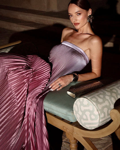 Model seated in the pink ombre Grizel strapless pleated maxi dress, angled view
