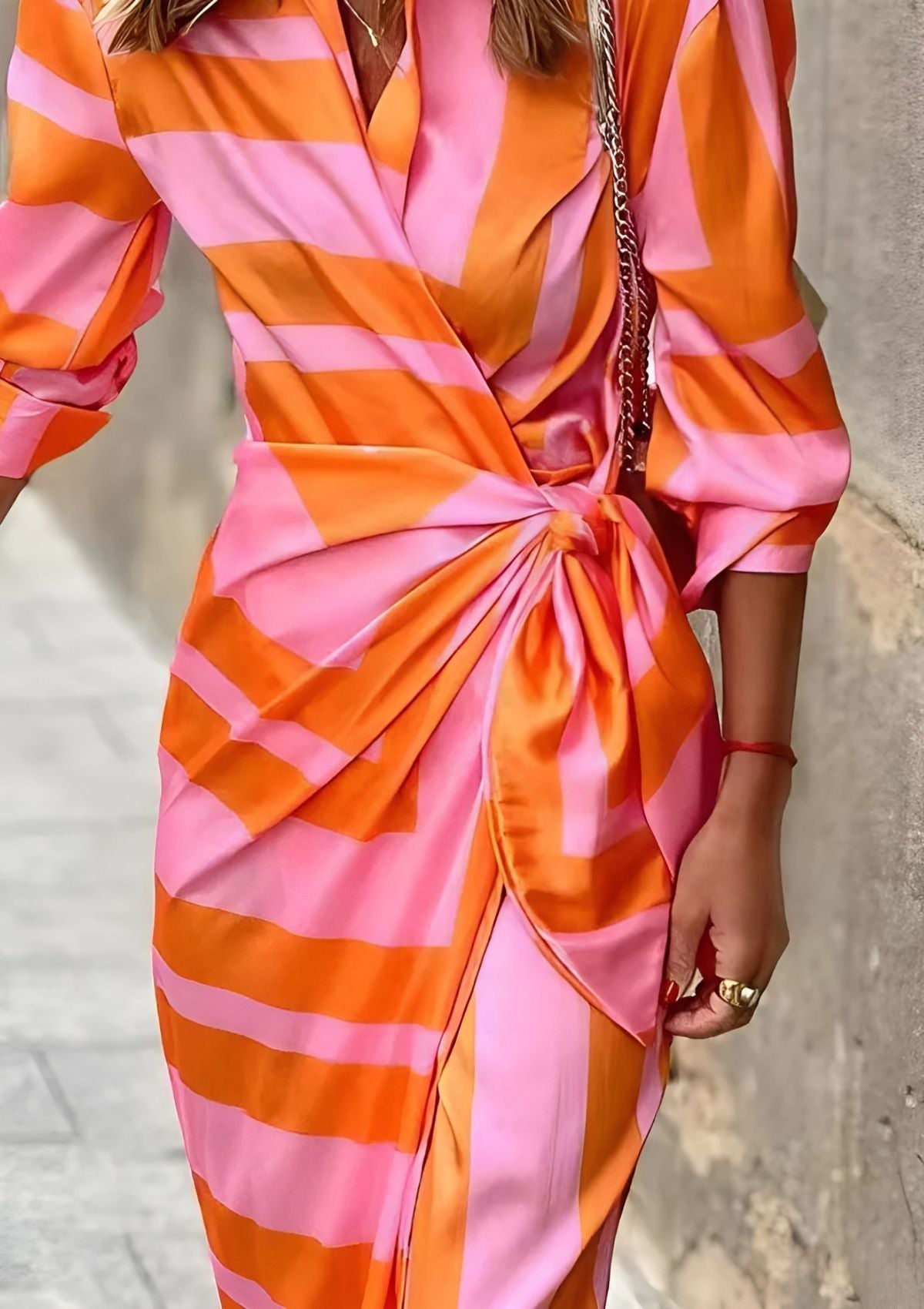 Close-up of the knotted wrap waist detail on the orange Sassa midi dress