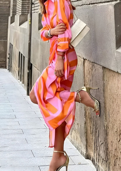 Side view of model walking outdoors in the orange Sassa wrap midi dress